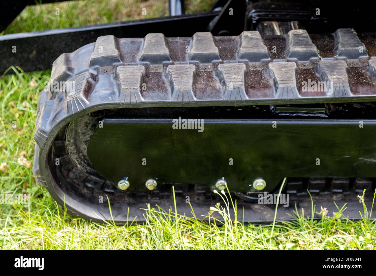 Eine Nahaufnahme eines Gummirachens an einem Minibagger zeigt ein tiefes Profildesign, das für Halt auf Boden, Gras und unebenem Gelände entwickelt wurde. Stockfoto
