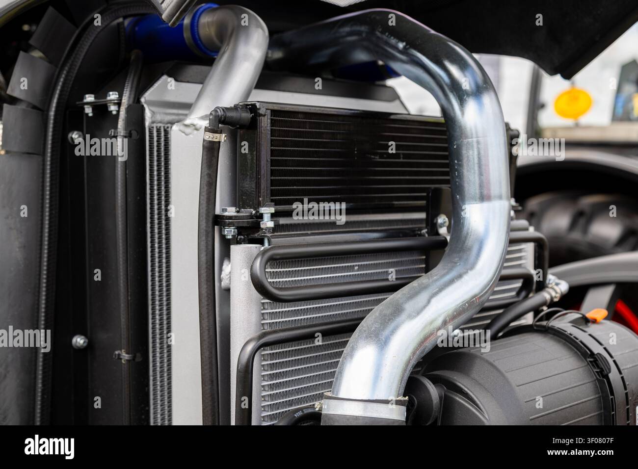 Eine detaillierte Ansicht betont ein Traktormotor-Kühlersystem unter einer geöffneten Motorhaube. Das landwirtschaftliche Maschinenteil Stockfoto
