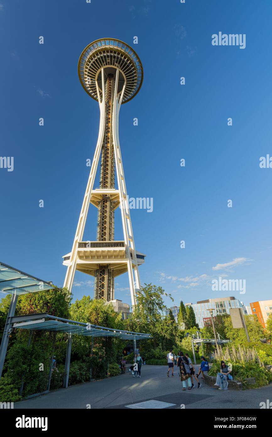 Washington Staat, Vereinigte Staaten, 20. JUN 2026 - Der ikonische Space Needle Turm erhebt sich über grüne Bäume und einen gepflasterten Gehweg, auf dem Menschen spazieren gehen Stockfoto