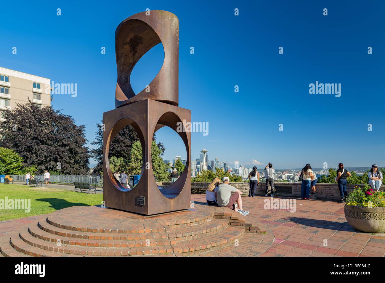 Washington State, 21. Juni 2026 - die abstrakte Skulptur aus rostfarbenem Metall steht auf einer Backsteinplattform in einem Park und bietet Besuchern einen Blick auf die Skyline von Seattle Stockfoto