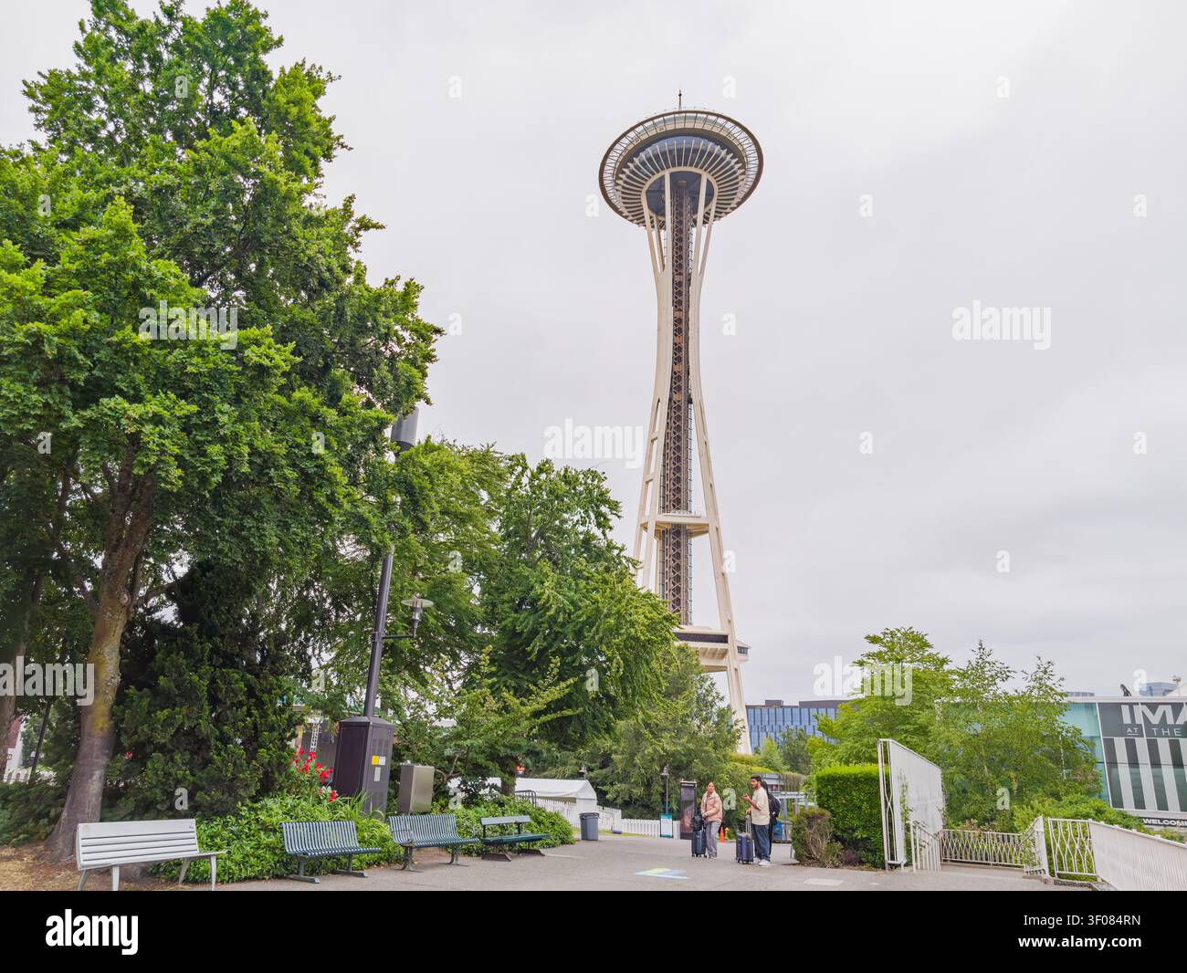Washington State, USA, 20. Juni 2026 - der legendäre Space Needle Tower steht hoch vor einem bewölkten Himmel, eingerahmt von üppigen grünen Bäumen und Park Stockfoto