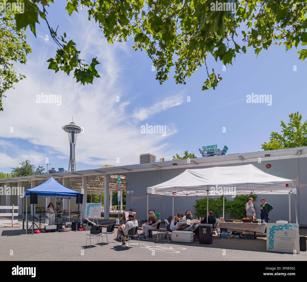 Washington State, USA, 21. Juni 2026 - Menschen, die sich unter weißen Zelten bei einer Veranstaltung im Freien versammeln, wobei die Space Needle im Hintergrund sichtbar ist Stockfoto