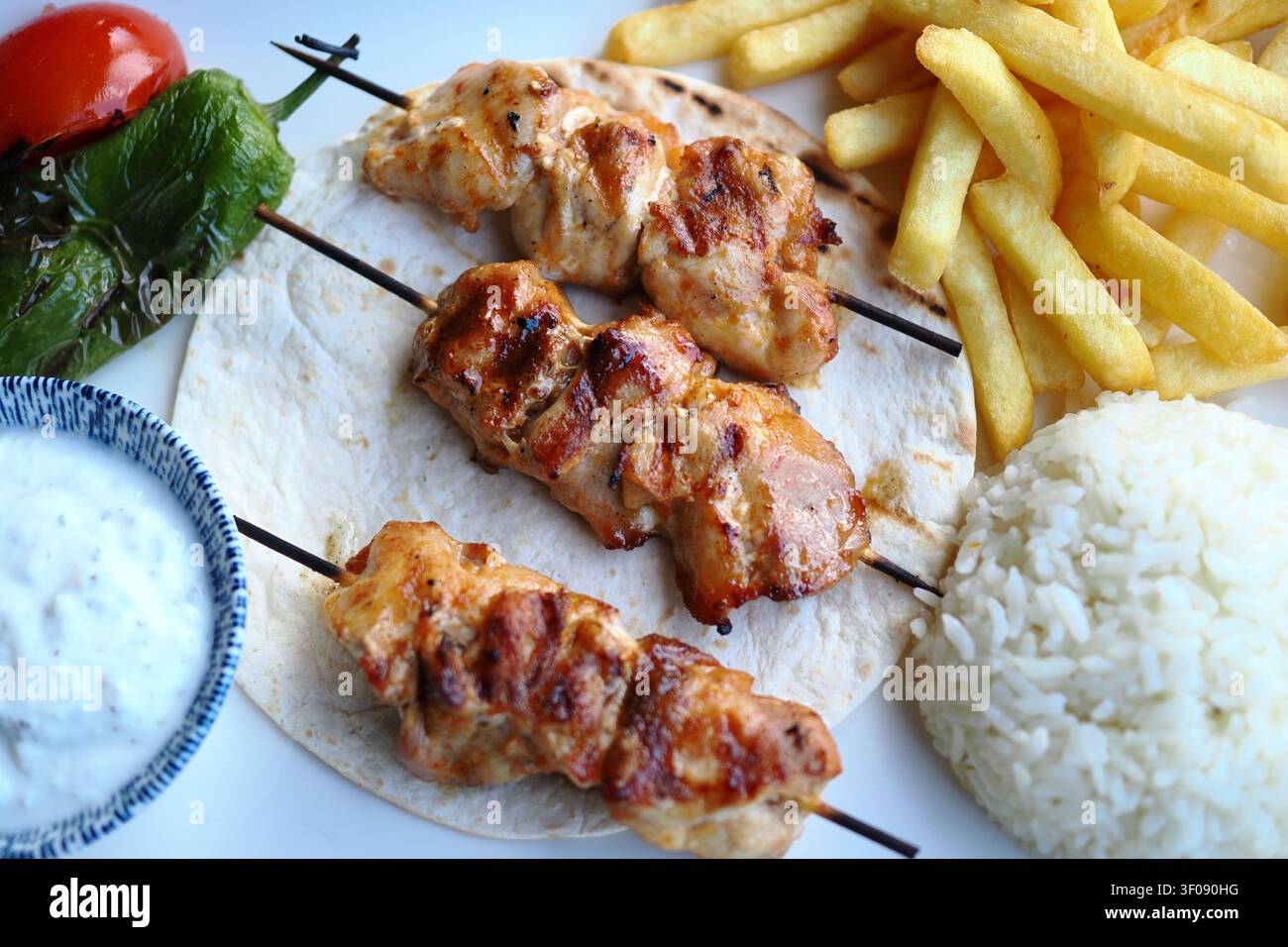 Leckere gegrillte Hühnerspieße mit herzhaften Beilagen Stockfoto