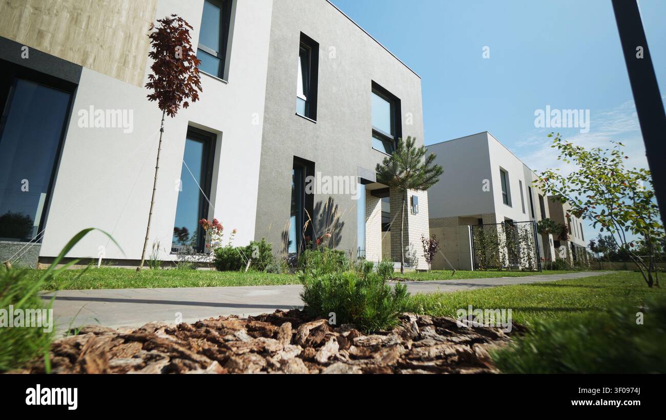 Moderne Reihenhäuser mit zeitgenössischem architektonischem Design und gepflegten, landschaftlich gestalteten Gärten an einem sonnigen Tag Stockfoto