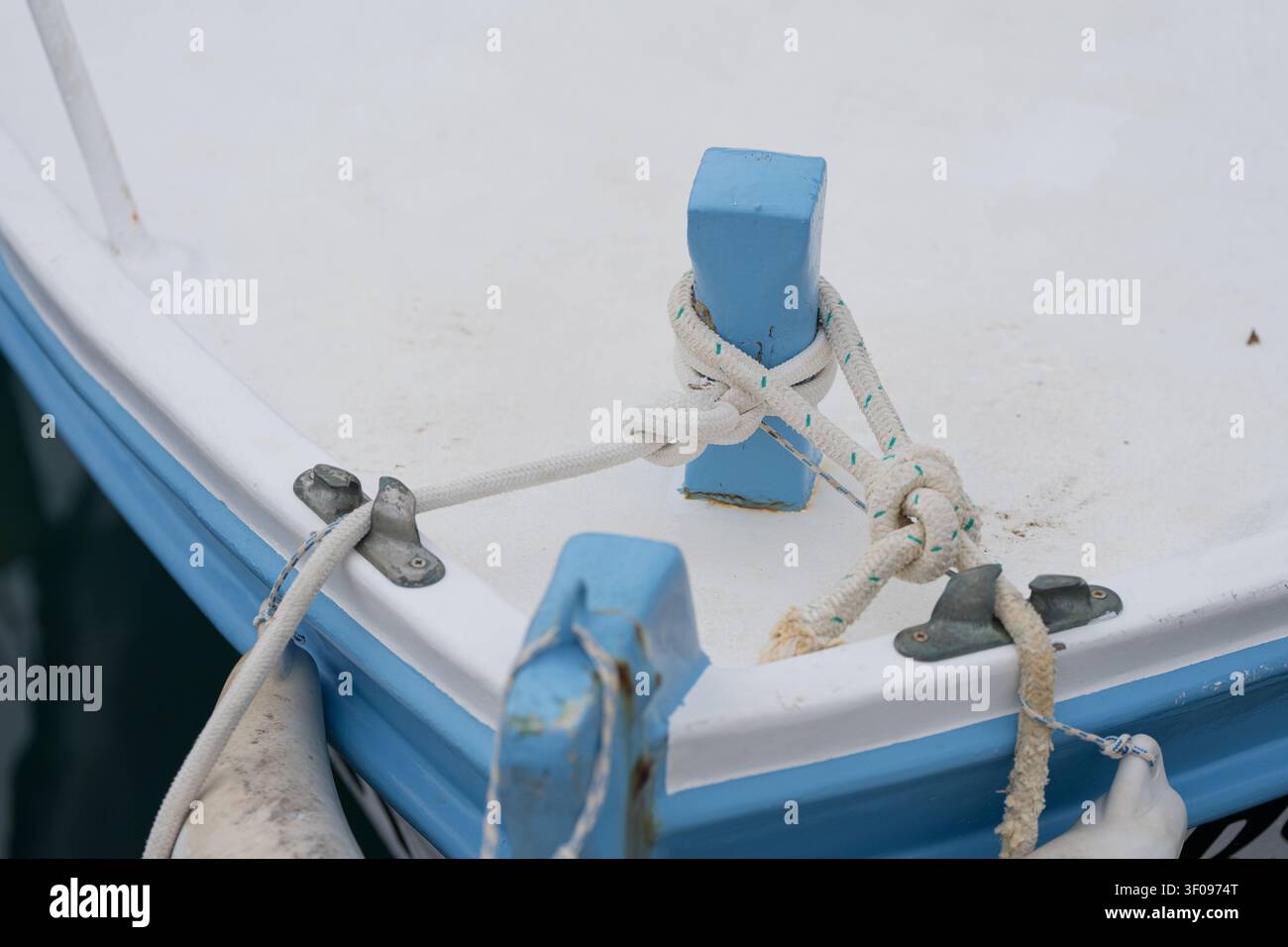 Seil an einem blauen Pfosten festgebunden, sicher befestigt, auf einem Bootsdeck, mit blauem Pfosten, weißem Seil, Bootsdeck, mit Plastik, Baumwolltextur, aus einer Nahaufnahme von oben Stockfoto