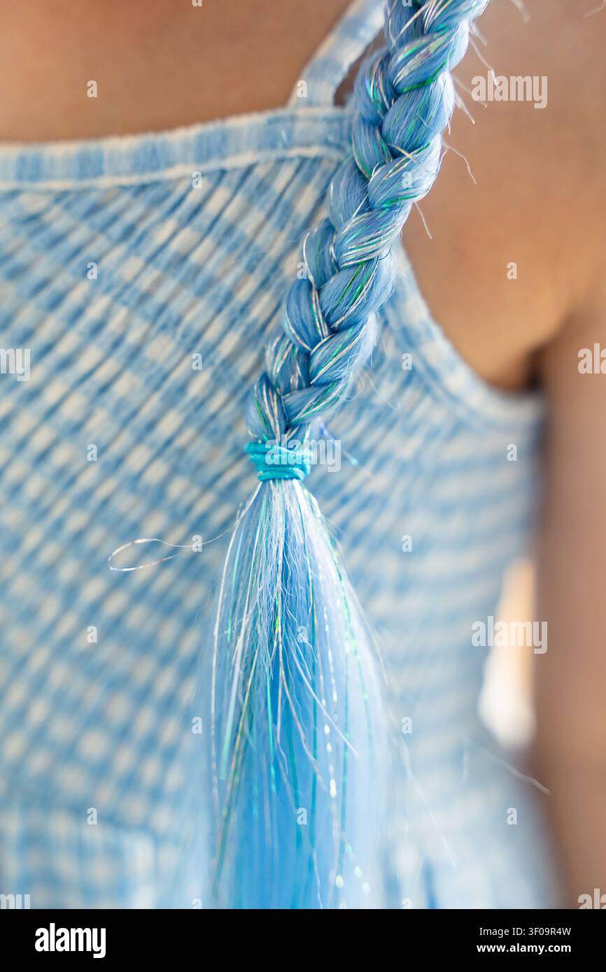 Nahaufnahme von blauen synthetischen Haarverlängerungen, die in eine Kinderfrisur eingeflochten sind und bunte Haarsträhnen zeigen. Haargestaltung und Selbstdarstellung spiegeln sich wider Stockfoto