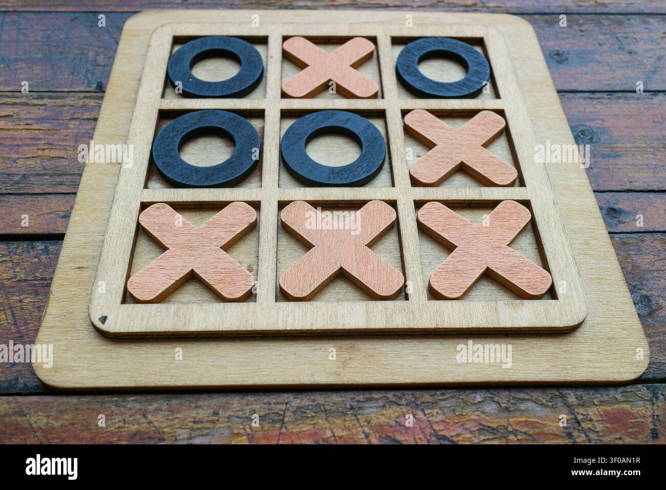 Vintage-Holztisch Tic-Tac-Toe-Brett auf rustikalem Holztisch zeigt Gewinnmuster. Nahaufnahme-Strategiespielkonzept mit natürlicher Textur. Stockfoto