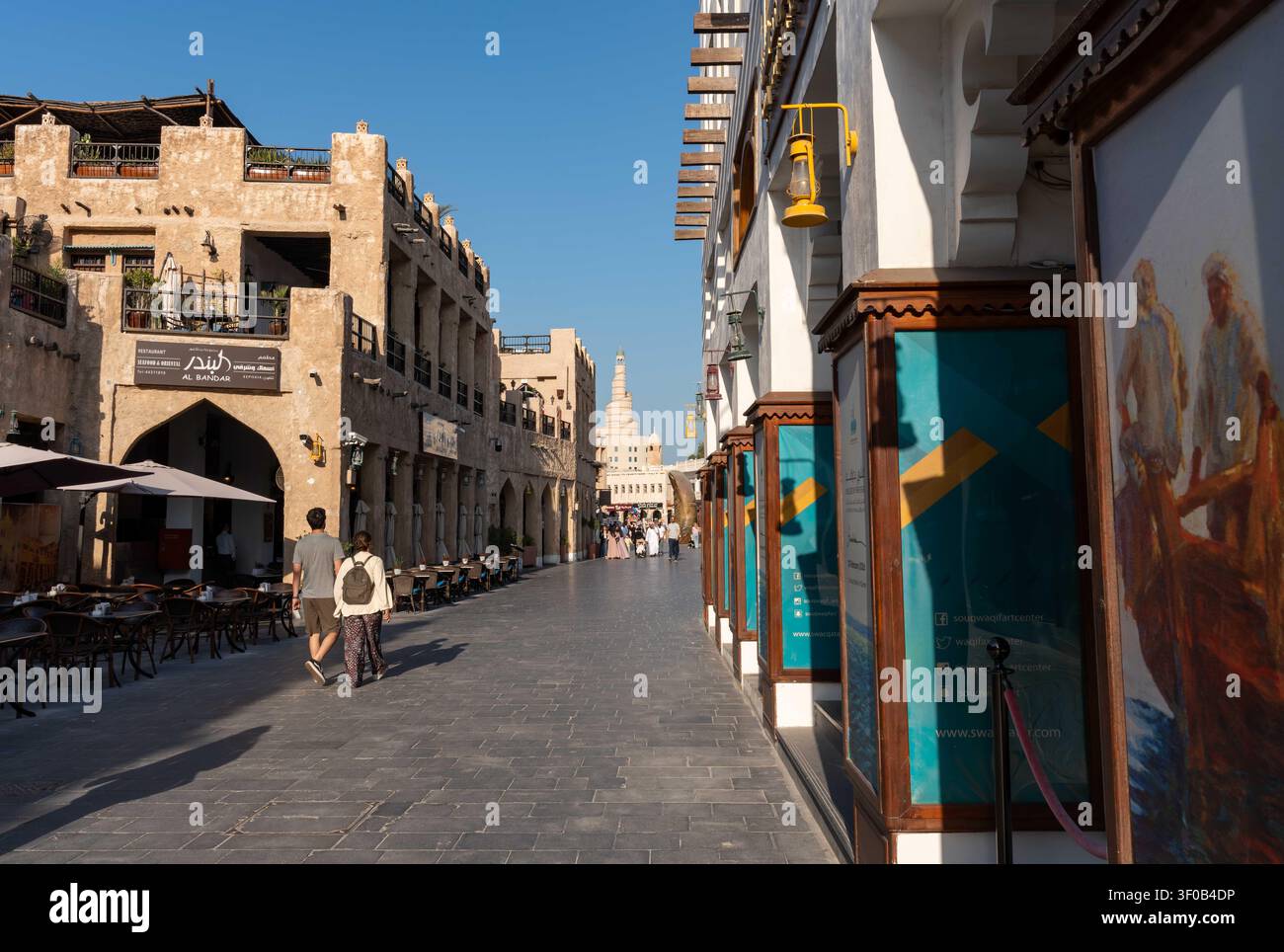 DOHA, KATAR - 14. FEBRUAR 2026: Weite Ansicht eines Touristenpaares, das den stein gepflasterten Weg des Souq Waqif in Doha, Katar, entlanggeht. Stockfoto