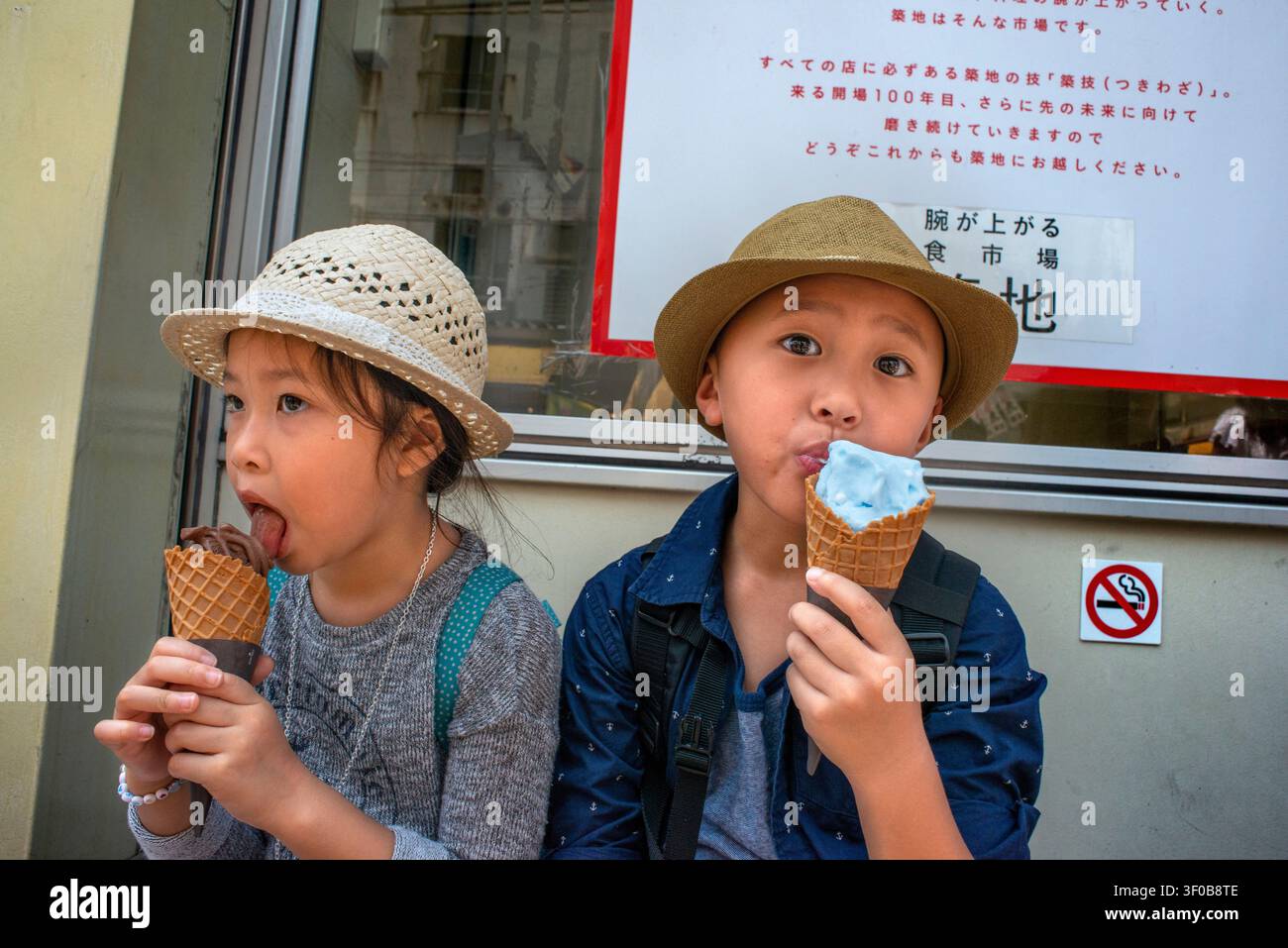 Kinder genießen Eis in der Nähe des Tsukiji-Außenmarktes in Tsukiji, Chuo City, Tokio, Japan. Zwei Kinder essen bunte Eistüten, während sie Stockfoto