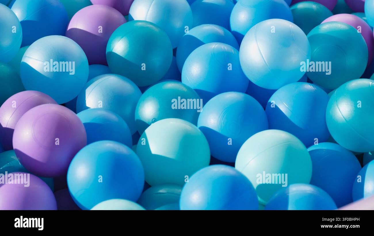 Bunte Plastikbälle in Blautönen und Violettönen bilden einen verspielten Hintergrund Stockfoto