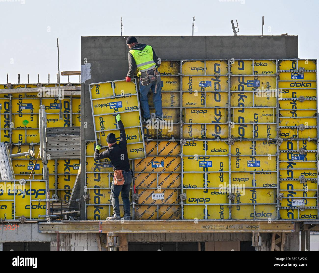 Bauarbeiter montieren gelbe Doka-Schalplatten für eine Betonwand auf einer Baustelle in Prag, Tschechische Republik. Stockfoto