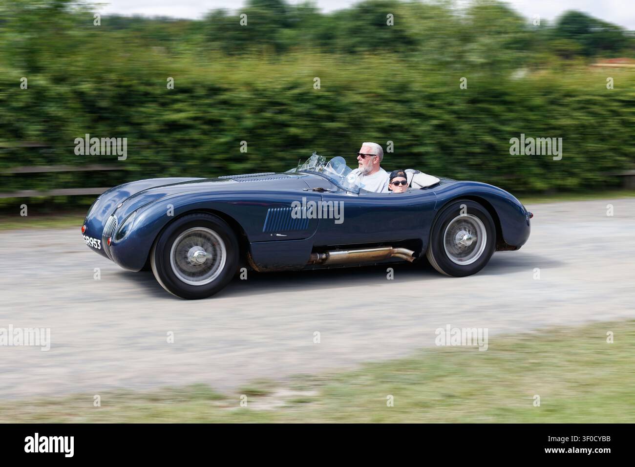Dunkelblauer Jaguar C-Type-Klassiker als Sportwagen auf einer Strecke mit Bewegungsunschärfe Stockfoto