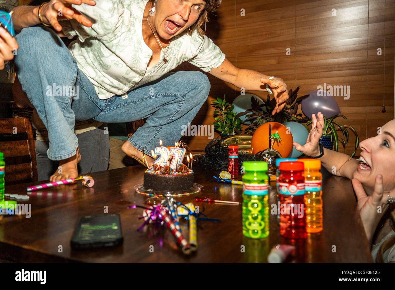 Geburtstagsfeier mit Kuchen, Kerzen, Luftballons und Gästen um den festlichen Tisch Stockfoto