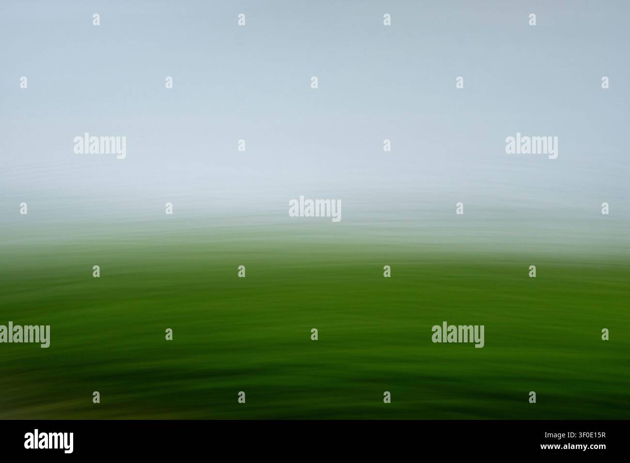 Minimalistische abstrakte Landschaft durch absichtliche Kamerabewegung (ICM). Lebendiges Smaragdgrün geht in weichen Schieferblaumist über mit flüssigem Horizontal Stockfoto