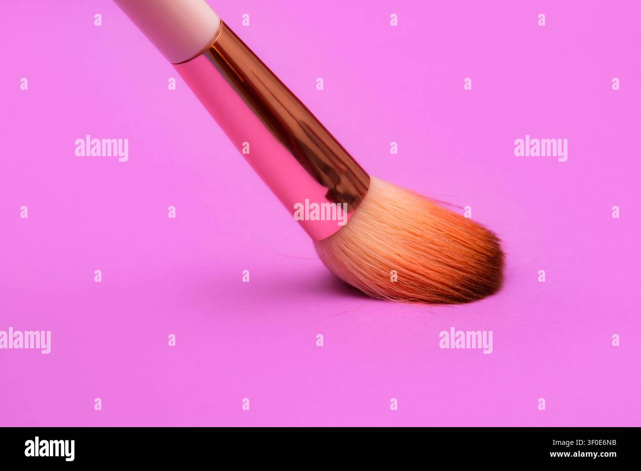 Make-up-Pinsel mit Roségoldgriff auf rosa Hintergrund platziert. Zeigt glatte Borsten, Kosmetikwerkzeug, Make-up-Pinsel und stilvolles feminines Design in Vibr Stockfoto