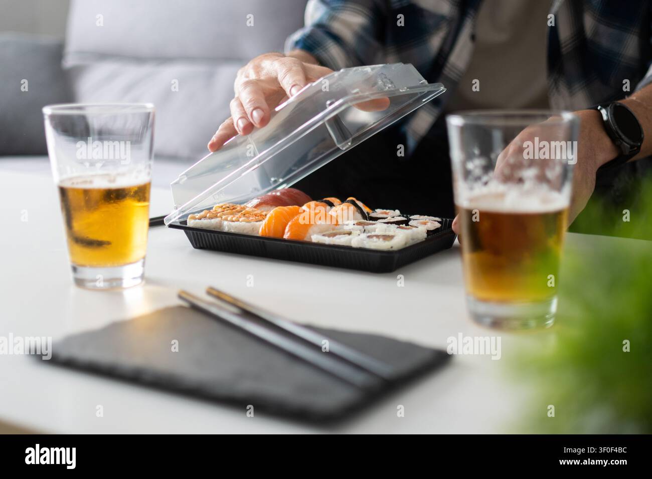 Ein Take-away-Sushi-Platte zu Hause öffnen mit Bier auf dem Tisch Stockfoto