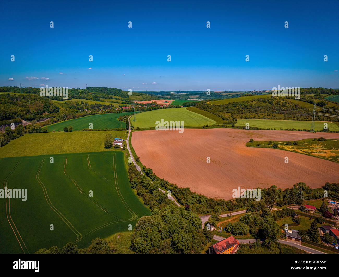 Felder und eine Landstraße in Thüringen, die Landschaft ist typisch für den Saale-Holzland-Kreis, es ist ein klarer Tag mit viel Sonnenlicht Stockfoto