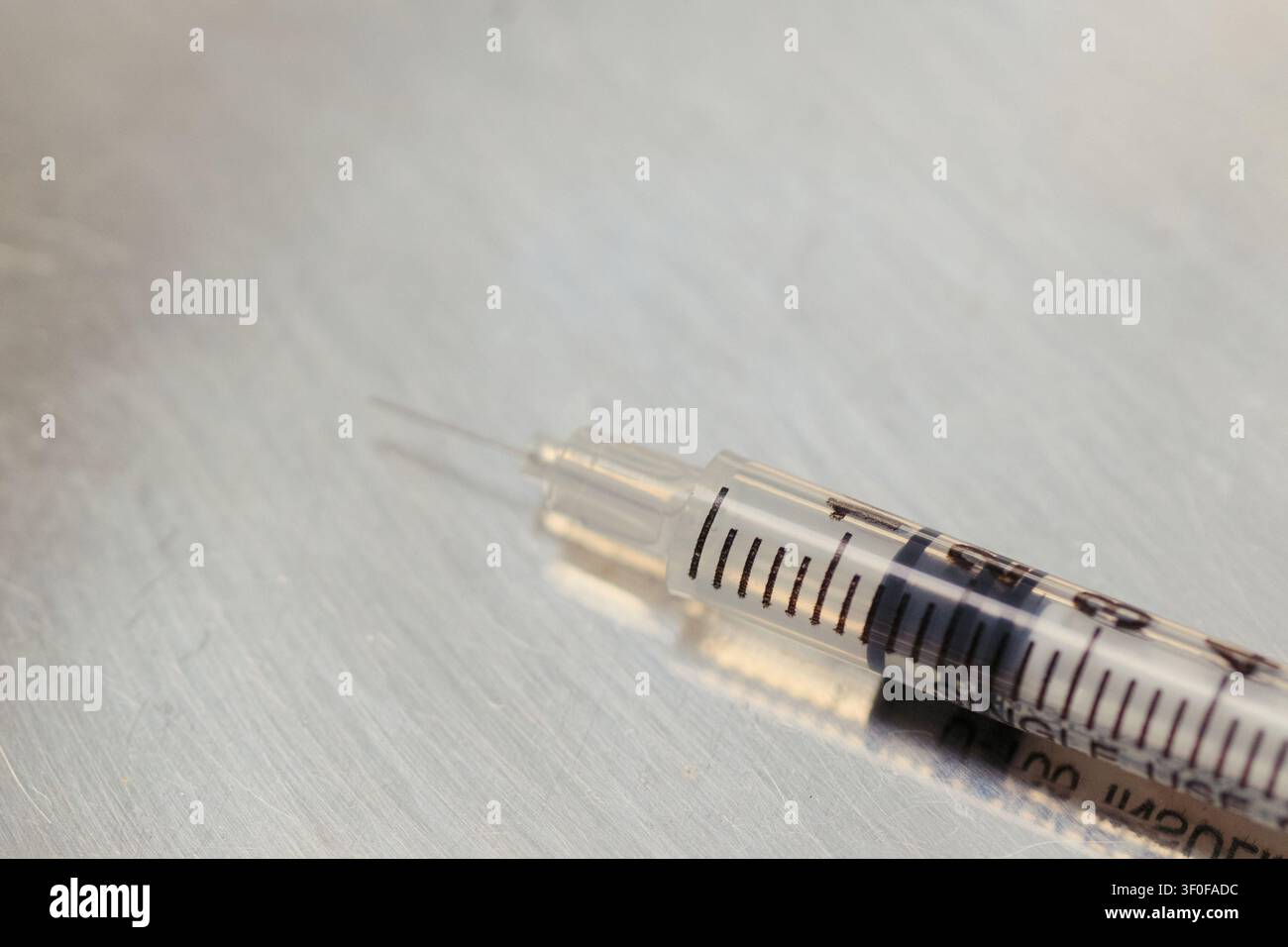 Nahaufnahme einer medizinischen Spritze, die auf einer Metalloberfläche ruht, repräsentiert Impfung, Injektion, Gesundheitsversorgung, steriles Verfahren. Ideal für medizinische Kampagnen, Klinik-Inhalte Stockfoto