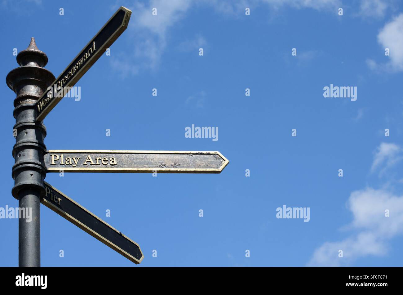 ein schwarzes Schild, das den Weg zum Spielplatz und zum Pier uk weist Stockfoto