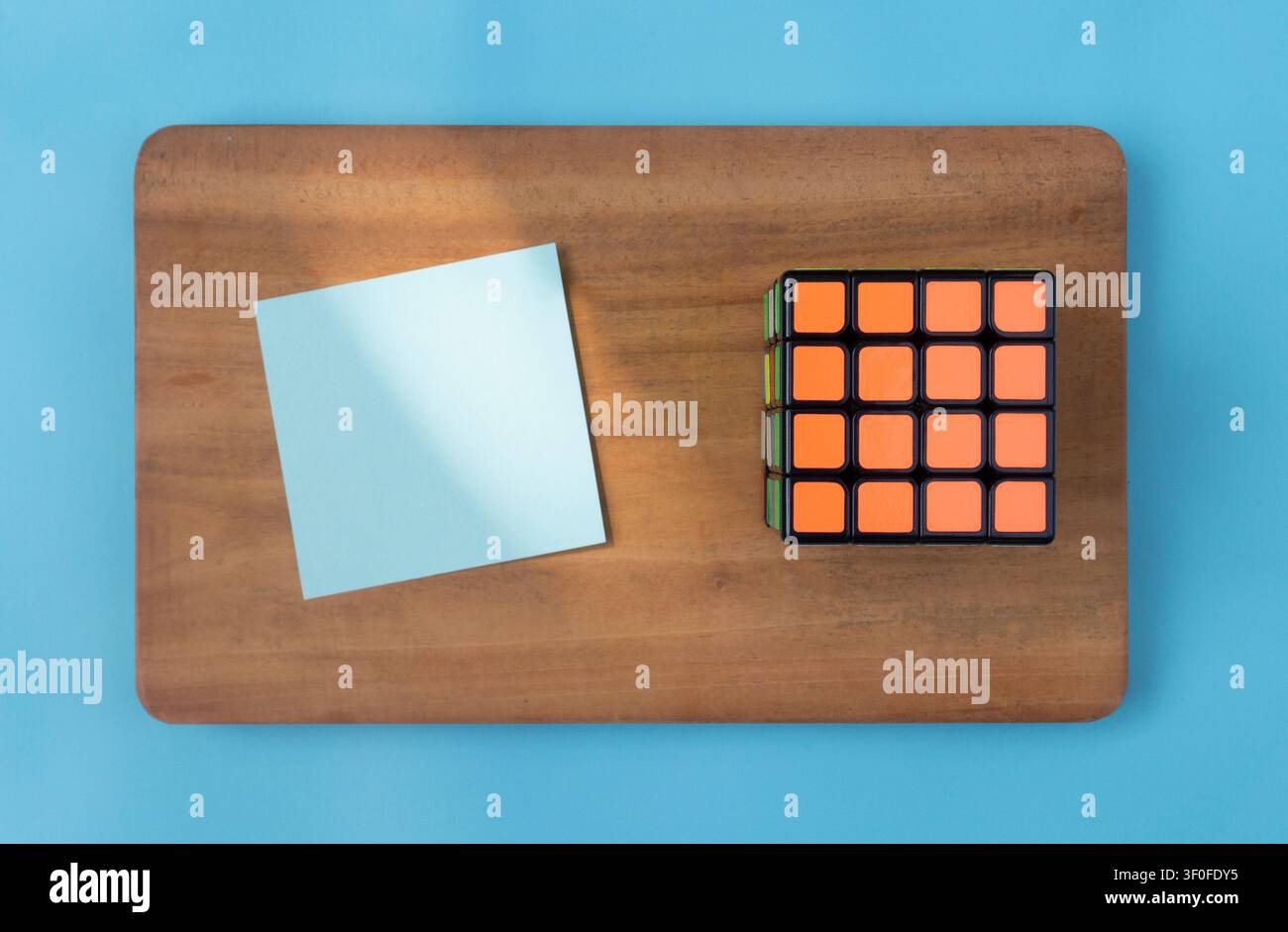 Blaue Haftnotiz und Rubik-Würfel auf Holzbrett Stockfoto