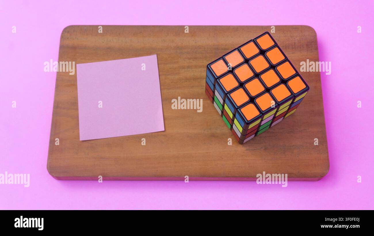 Rubik-Würfel und Haftnotiz auf Holzbrett Stockfoto