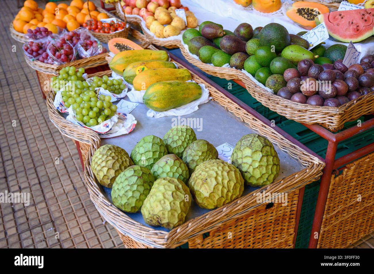 Ein lebhafter Obstmarkt auf der Insel Madeira mit einer farbenfrohen Auslage frischer tropischer und lokaler Früchte, darunter Zimtapfel, Papayas, Avocado. Stockfoto
