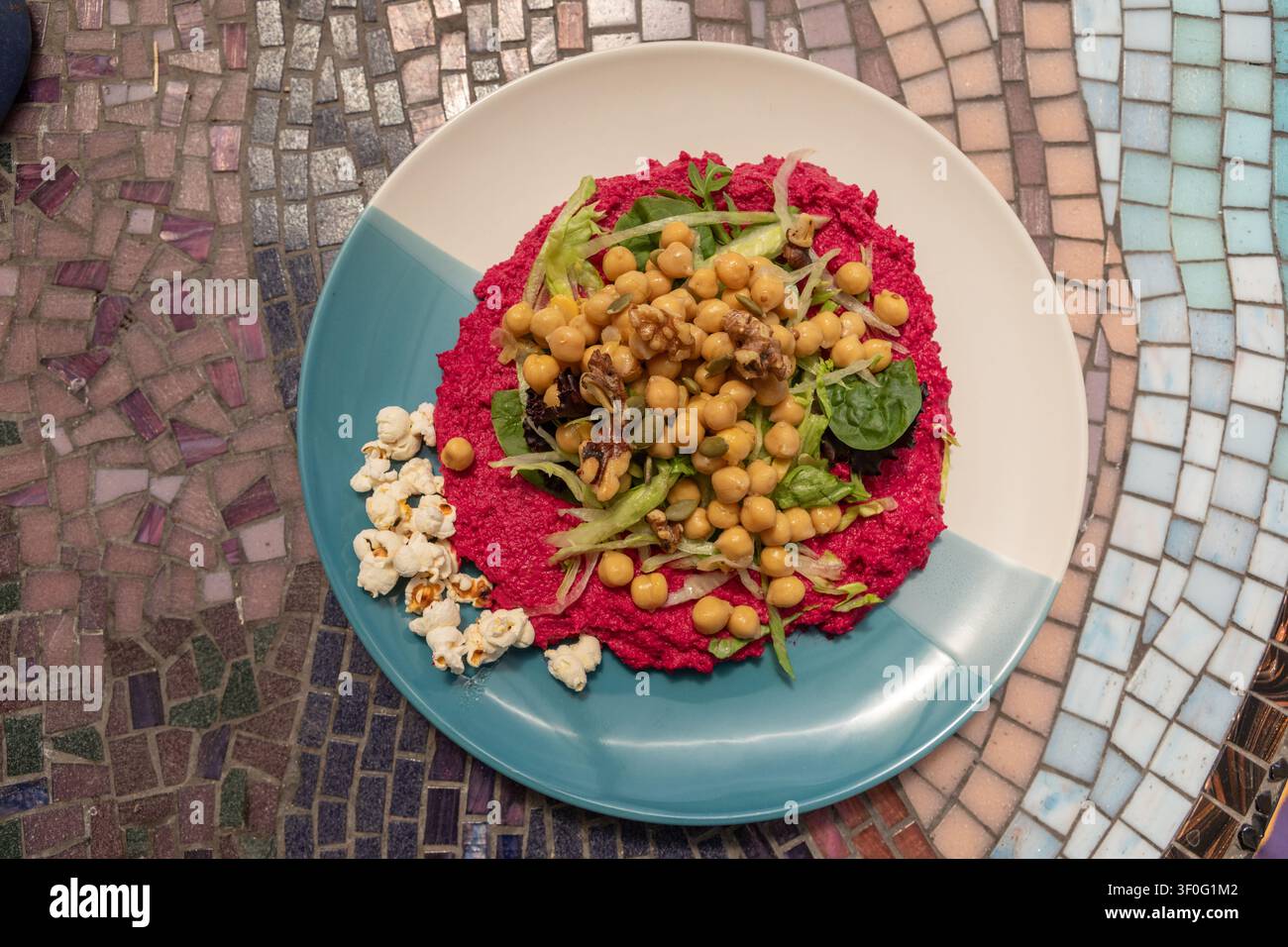 Kichererbsensalat und geröstete Walnüsse auf einem Bett aus köstlichem Rote-Bete-Hummus, mit Popcorn und einer Streuung von Sonnenblumenkernen Stockfoto