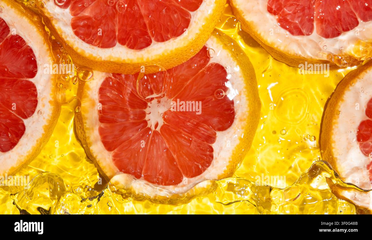 Makrotextur von rosa Grapefruit-Scheiben in Flüssigkeit mit Blasen und Wellen Stockfoto