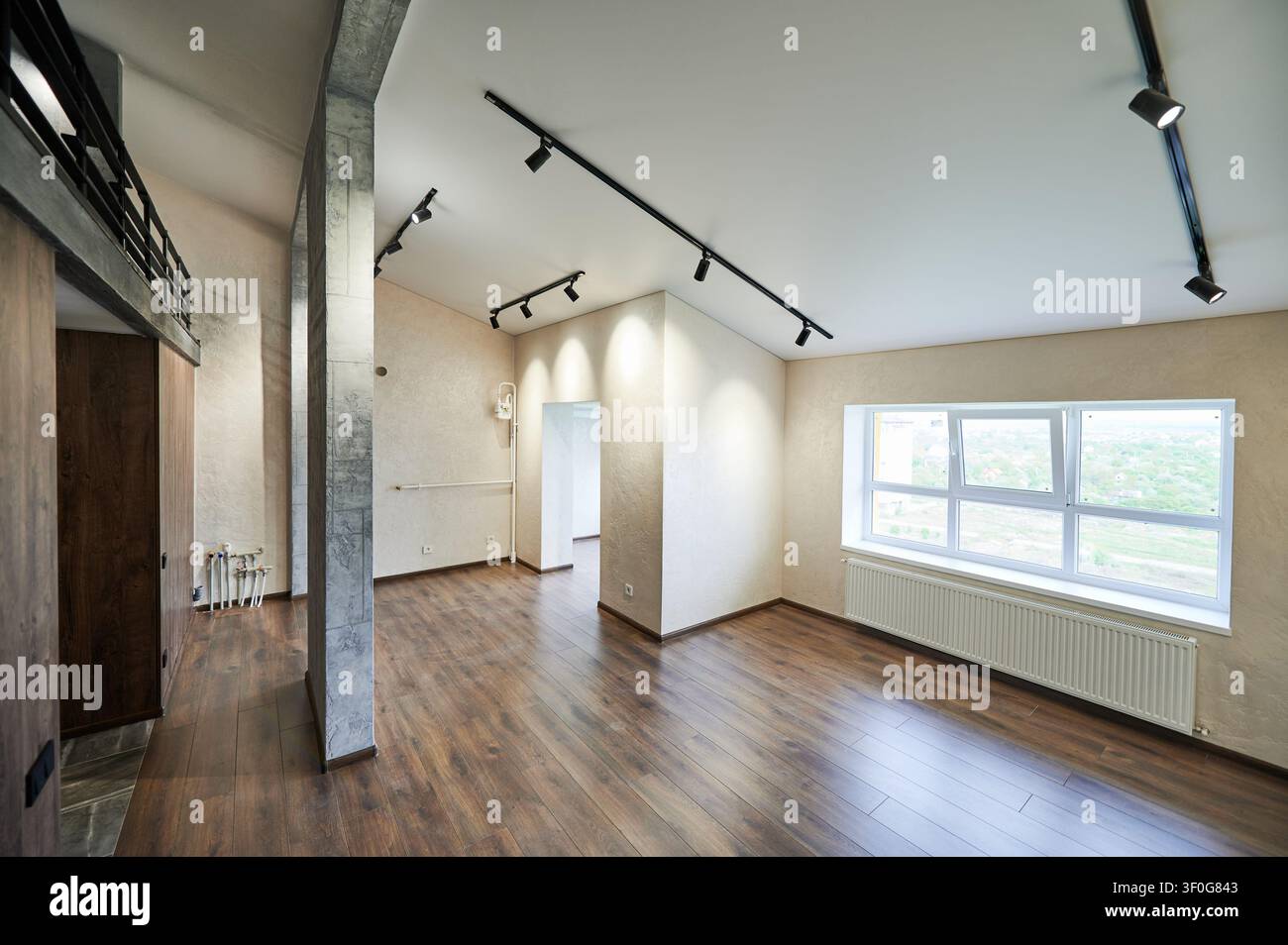 Geräumiger moderner Raum mit großem Fenster, Heizkörper und schwarzen Strahler, weite Aussicht auf leere Doppelhaushälfte innen. Zeitgenössisches Wohndesign, Renovierung und Immobilienkonzept Stockfoto