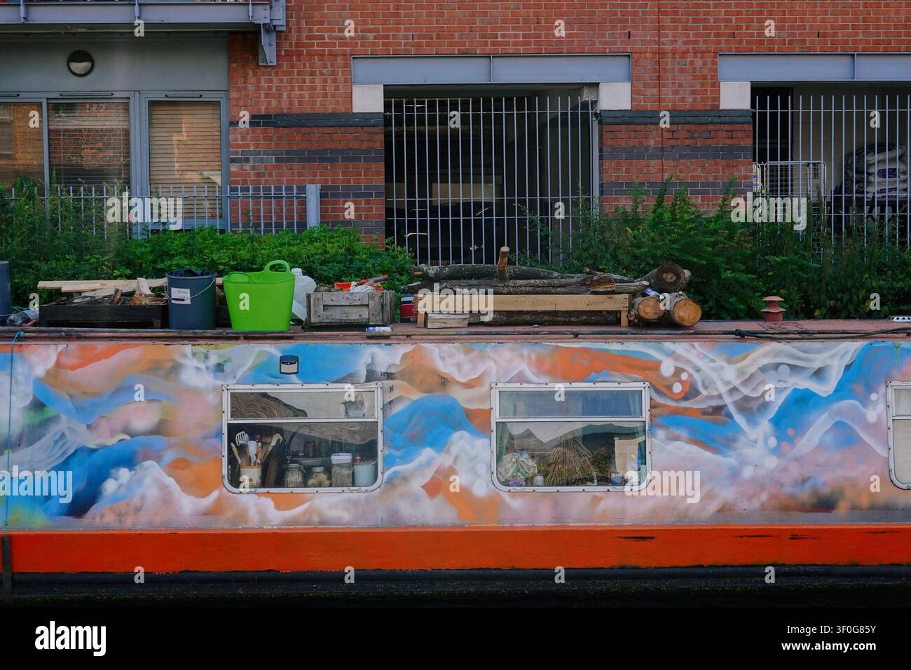 Nahaufnahme eines farbenfrohen, mit Graffiti bemalten Kanalboot-Rumpfes mit Fenstern und Dachlagerung in Birmingham, UK Stockfoto