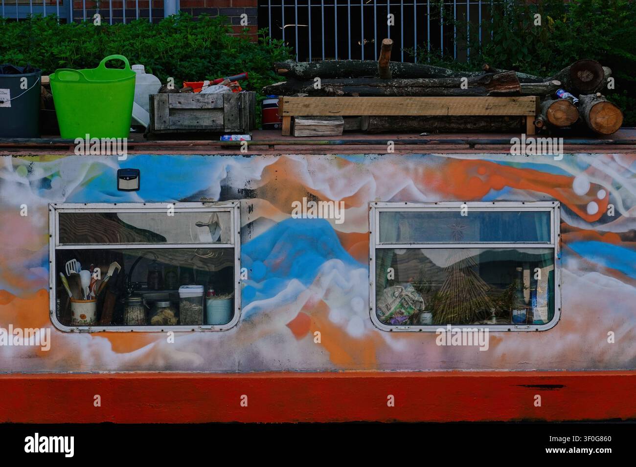Nahaufnahme eines farbenfrohen, mit Graffiti bemalten Kanalboot-Rumpfes mit Fenstern und Dachlagerung in Birmingham, UK Stockfoto