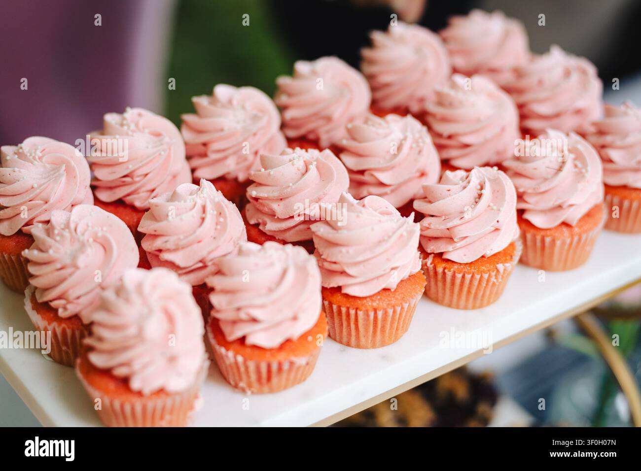 Reihen von rosa Cupcakes mit Spiralglasur auf weißem Teller Stockfoto
