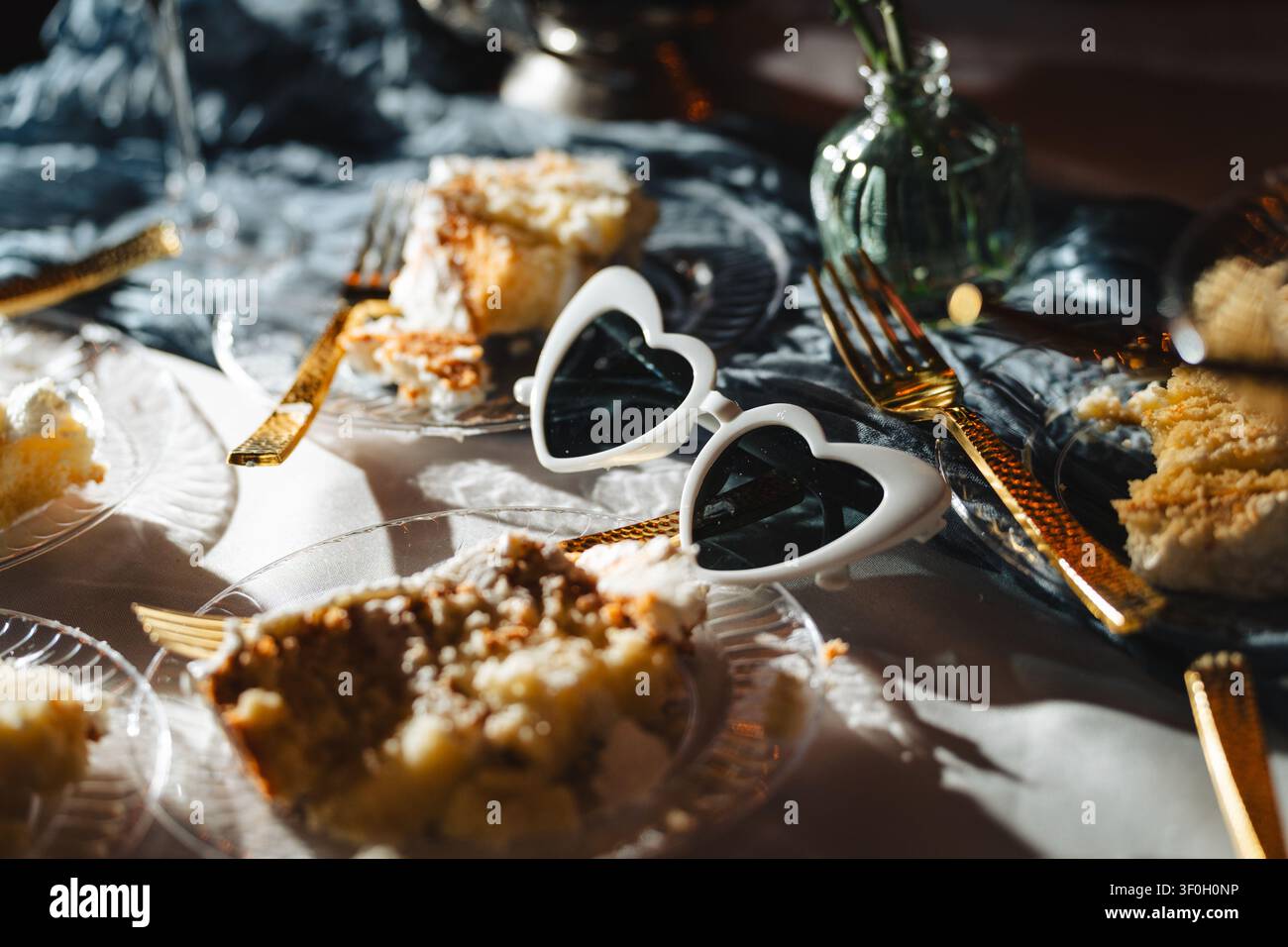 Herzförmige Sonnenbrillen und Kuchenstücke auf dem Hochzeitstisch-Setup Stockfoto