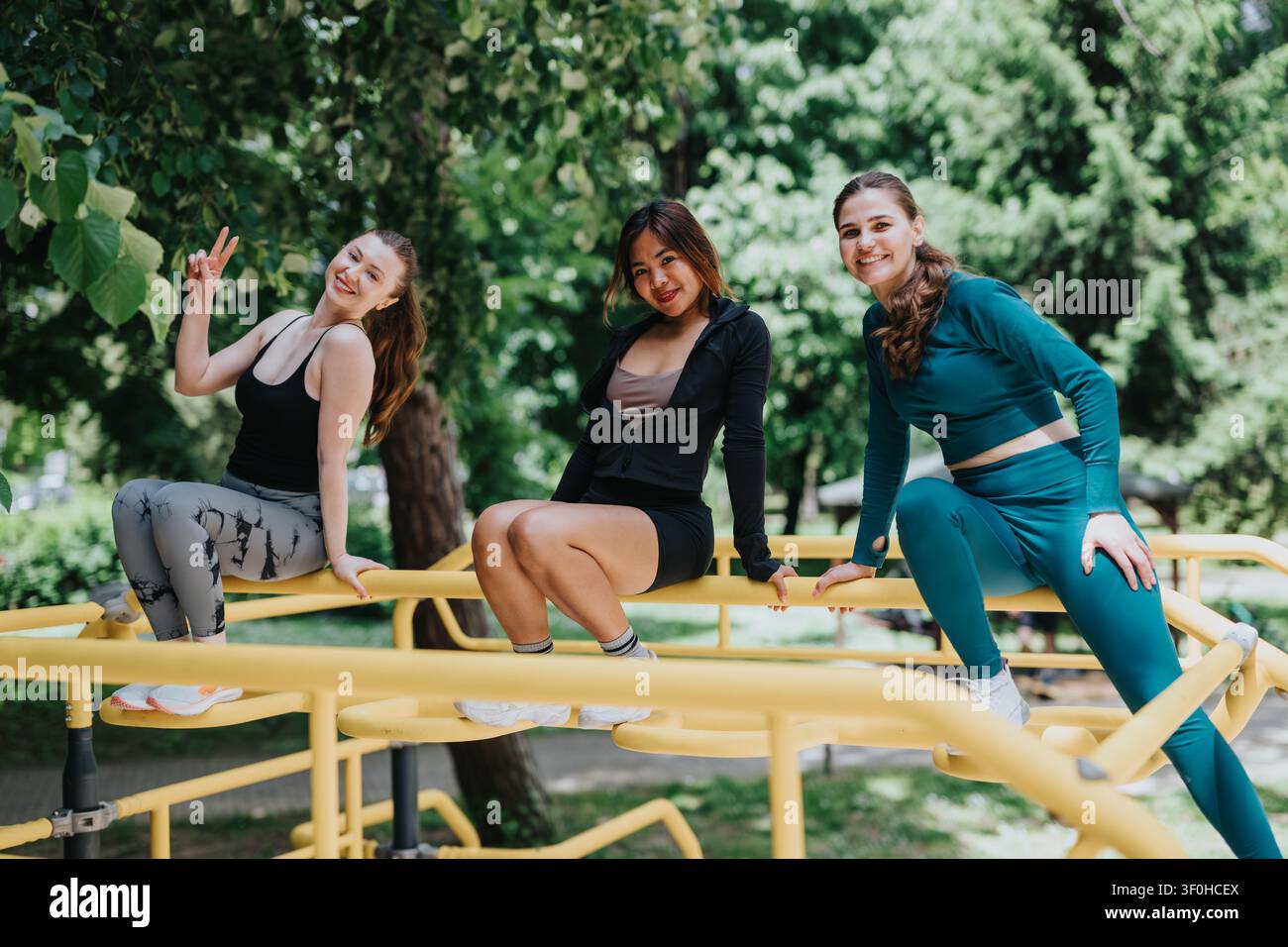 Drei Freunde trainieren draußen an Park-Fitnessgeräten und genießen ein lockeres Workout zusammen Stockfoto