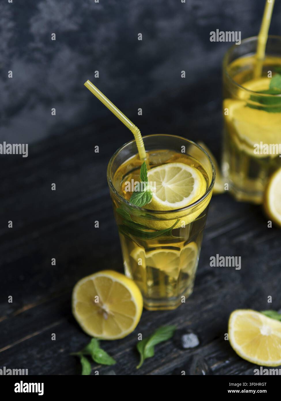Traditioneller geeister Zitronen- und Minze-Eistee. Mojito in zwei Gläsern auf einem dunklen Betonstisch Stockfoto