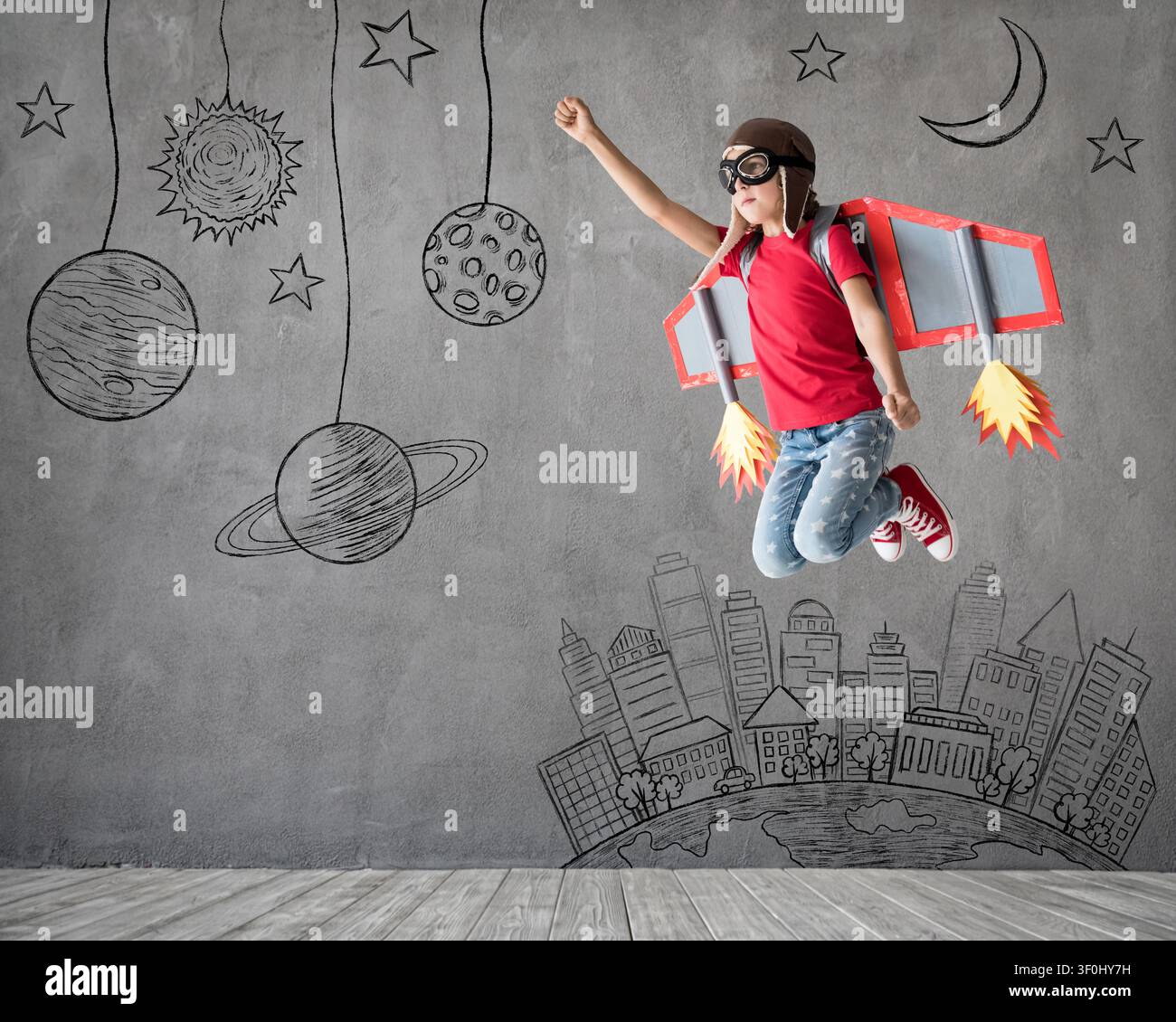 Glückliches Kind spielt mit Spielzeug-Papierflügeln. Kinderpilot hat Spaß zu Hause. Erfolg, Innovation und Weltraumkonzept Stockfoto
