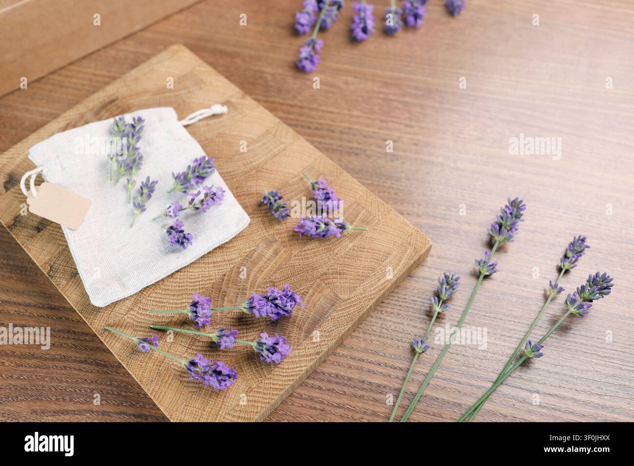 Handgefertigter Lavendelbeutel mit leerem Kraftanhänger auf Holz. Gemütlicher Heim Duft Aromatherapie Rohstoffpräsentation. Minimalistisch rustikal Stockfoto