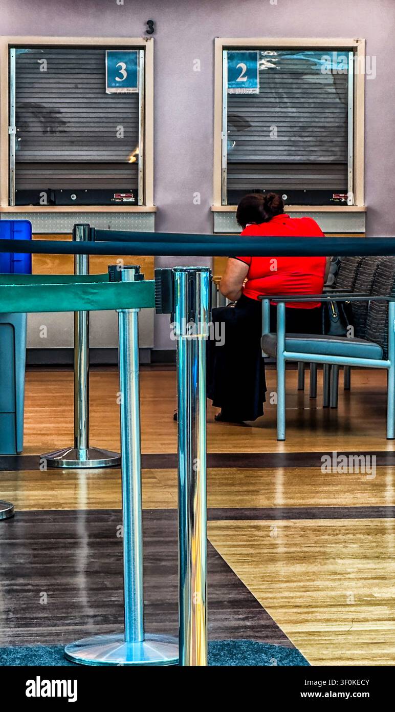 Eine Person ist in einem Wartebereich eines medizinischen Zentrums zusammengekauert. Stockfoto