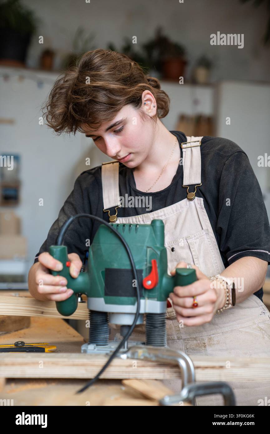 Begabte konzentrierte Restauratorin arbeitet in der Restaurierungswerkstatt mit einem Elektrofräswerkzeug. Stockfoto