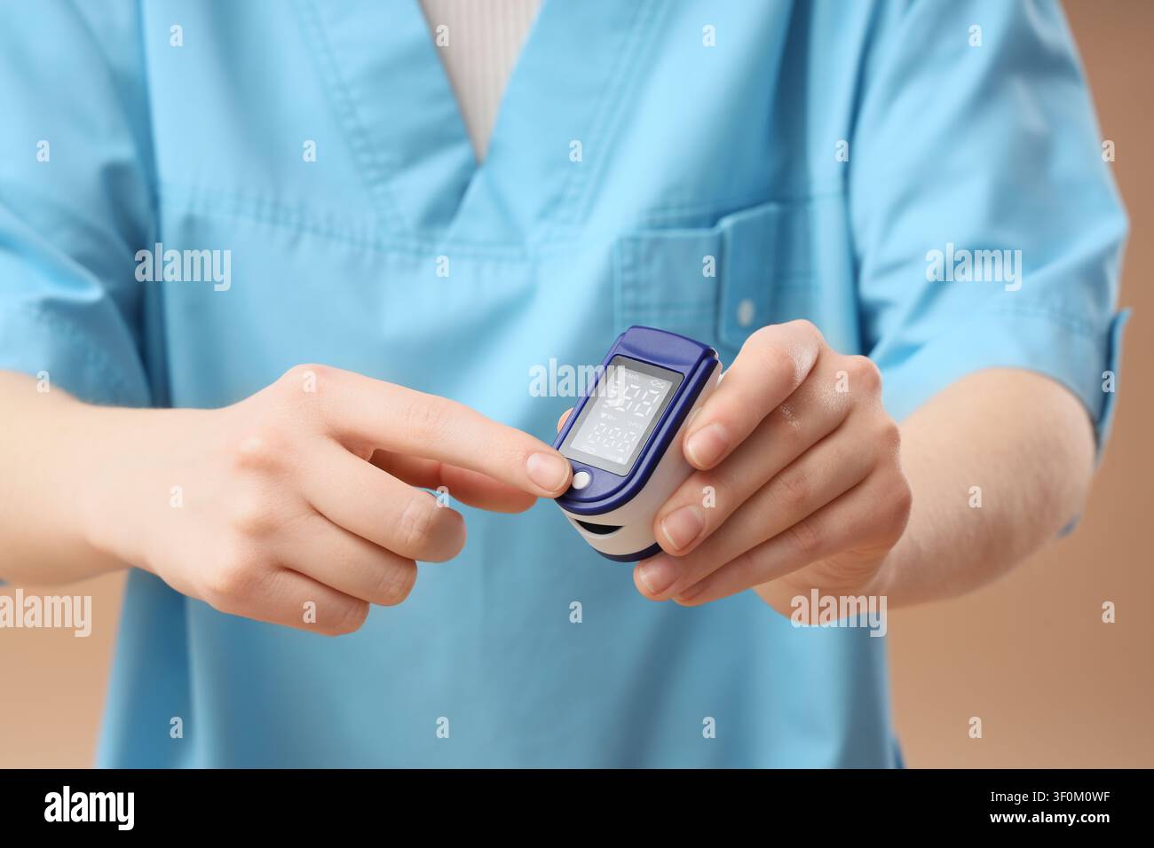 Mediziner in blauen OP-Kitteln hält ein Pulsoxymetriegerät, Konzept für Gesundheitsüberwachung und Patientenbetreuung, das Gerät wird zur Messung der Sauerstoffsättigung verwendet Stockfoto
