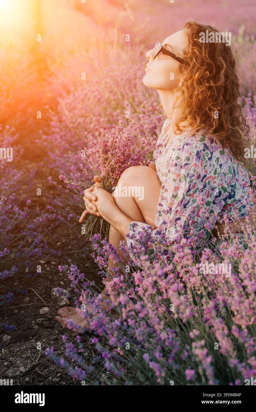 Lavendel-Frau-Blumen, junge Frau sitzt in einem Lavendelfeld und hält einen Blumenstrauß, während sie einen friedlichen sonnigen Sommernachmittag in der Provence genießt Stockfoto