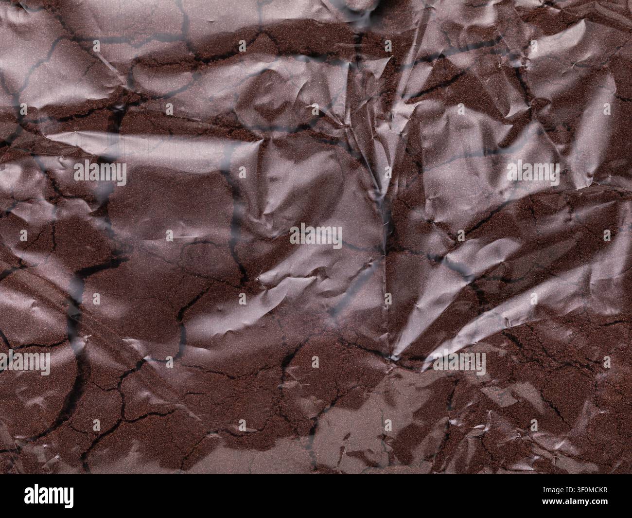 Hintergrund aus durchsichtigem zerknittertem Plastikbeutel, gefüllt mit braunem kinetischem Sand, Nahaufnahme Stockfoto