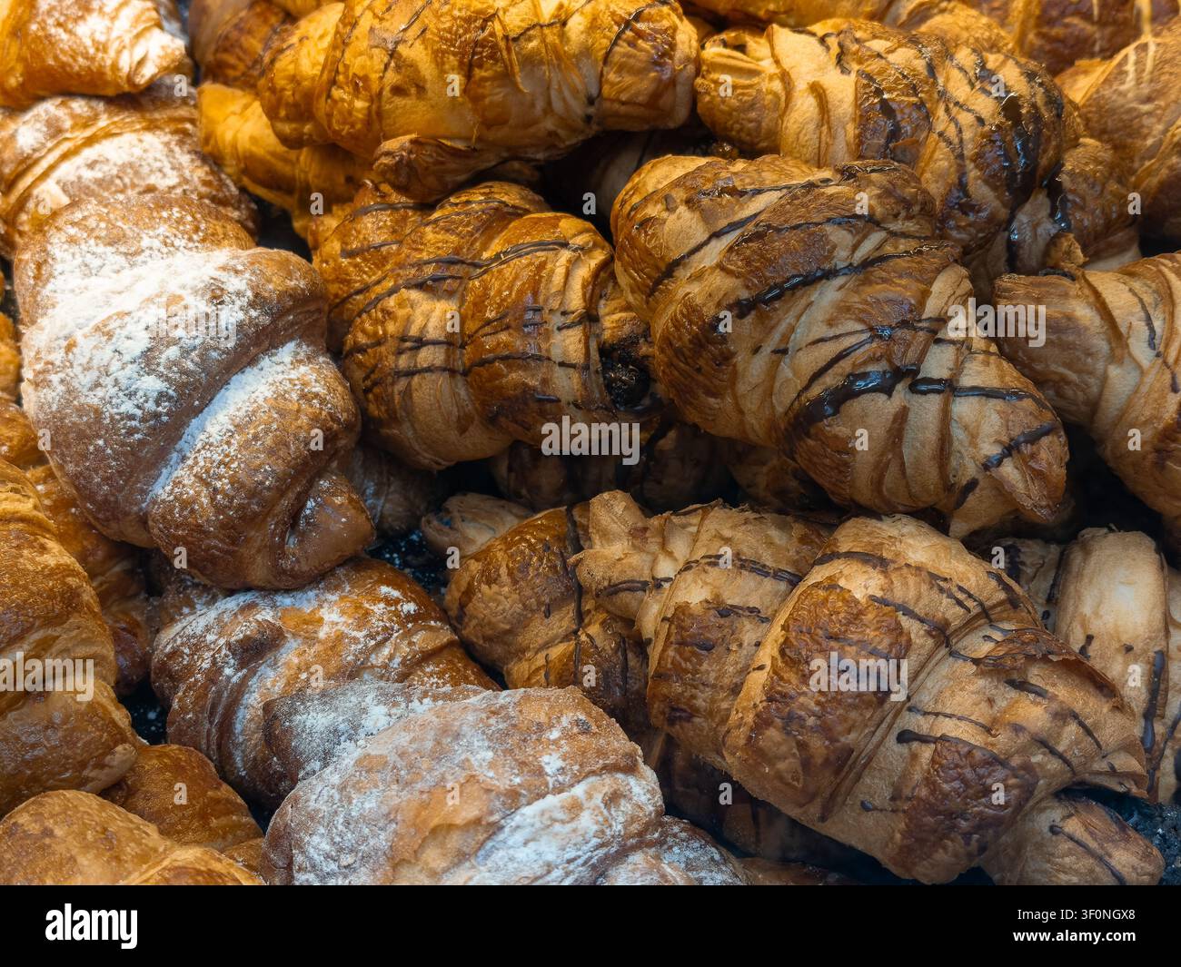 Knusprige goldene Buttergebäckstücke, glasiert mit reichhaltiger dunkler Schokolade oder mit Zucker bestäubt, in einer dichten Anordnung, die appetitliche Backwaren für Mo veranschaulicht Stockfoto