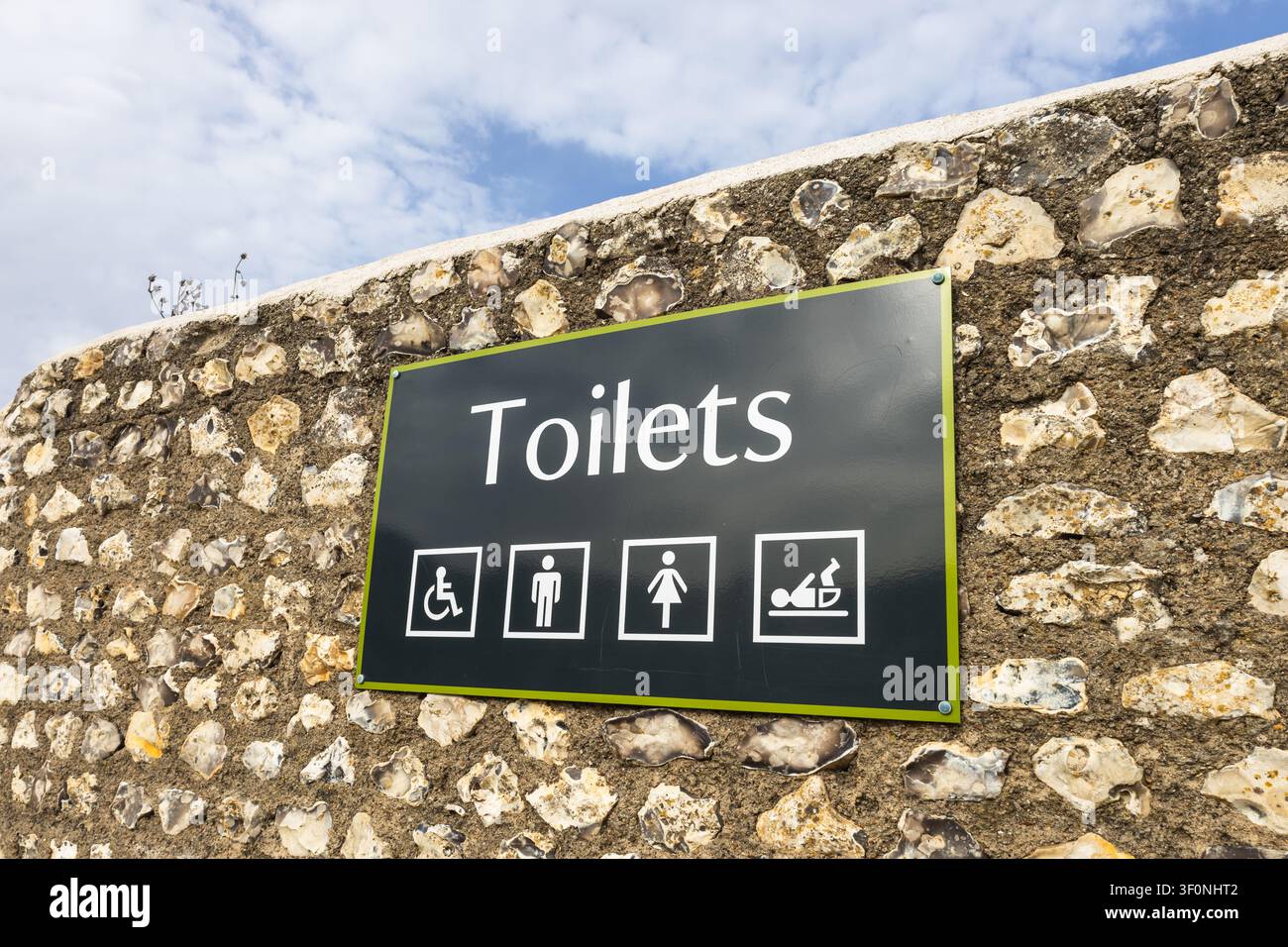 Öffentliche Toilettenschild an einer Steinmauer Stockfoto