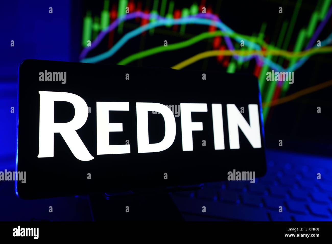 Redfin Corporation Ein Immobilienmakler Jetzt Teil von Rocket Companies Logo auf einem Smartphone-Bildschirm vor einem Computer, der die Börsenfinanzierung anzeigt Stockfoto