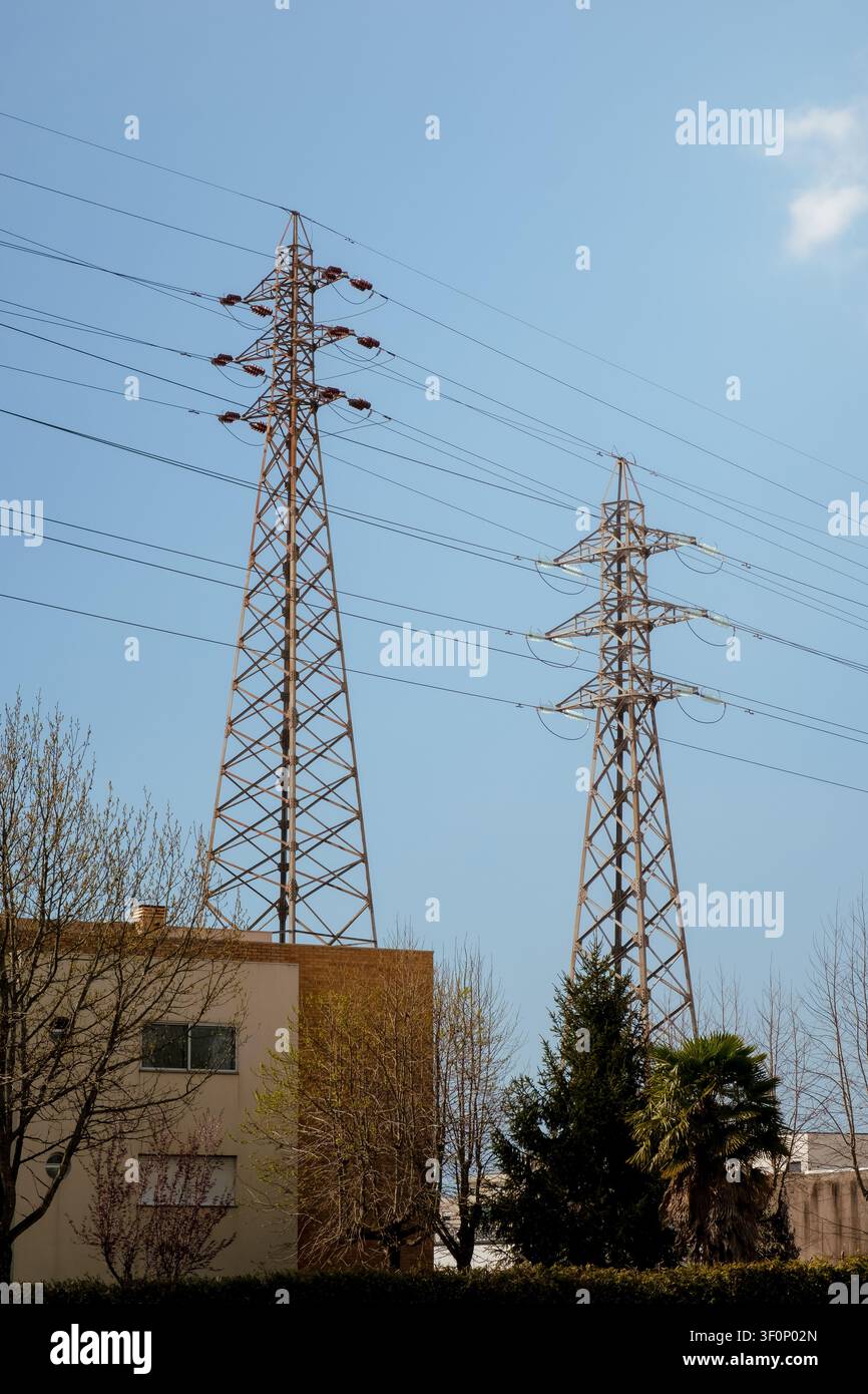 Zwei Strommasten, die Strom über eine städtische Landschaft verteilen Stockfoto