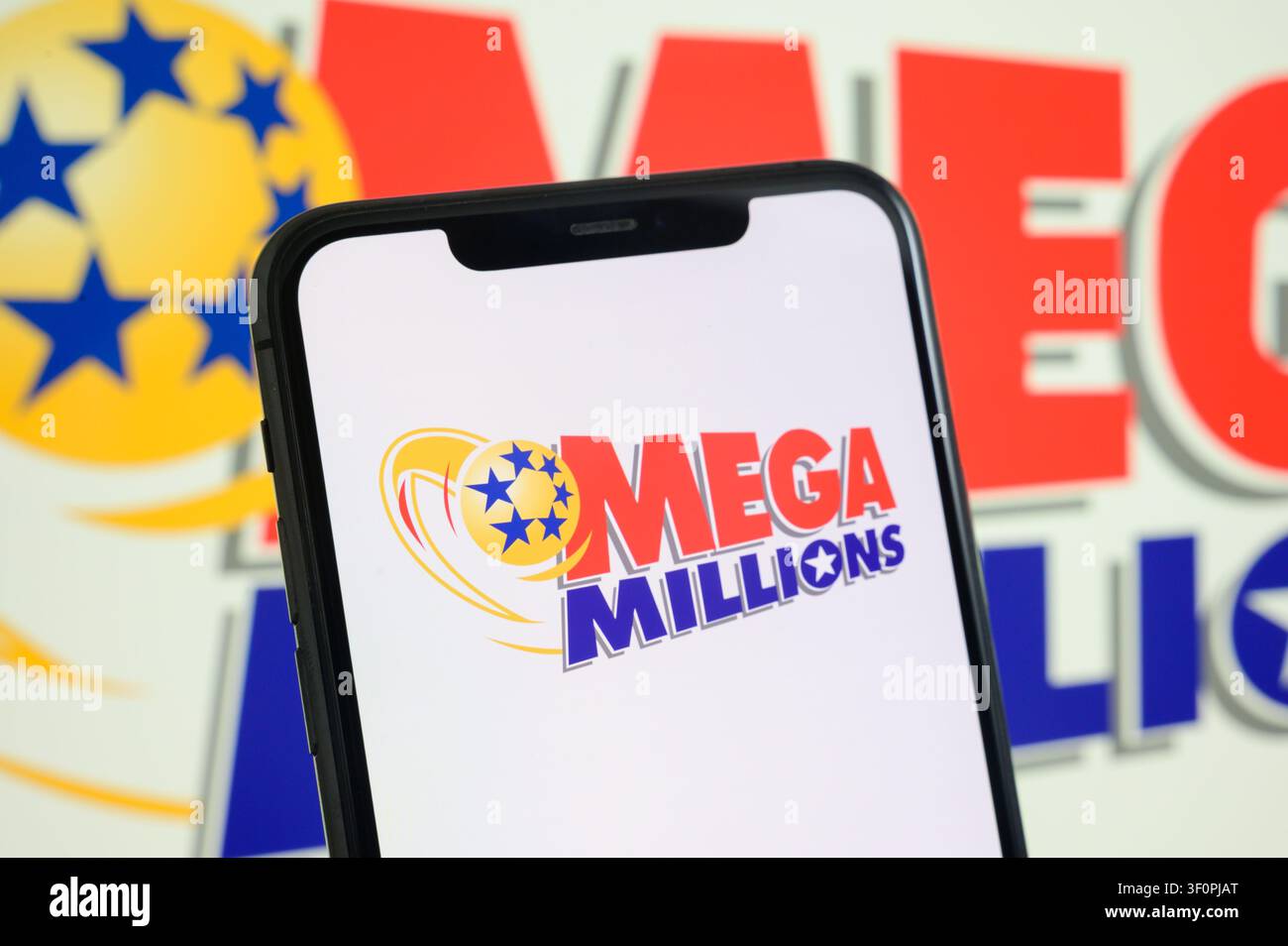 Paris, Frankreich - 9. Juli 2026: Ein Smartphone, das das Mega Millions-Logo auf dem Bildschirm anzeigt, vor einem Hintergrund mit dem Lotterie-Logo. Stockfoto