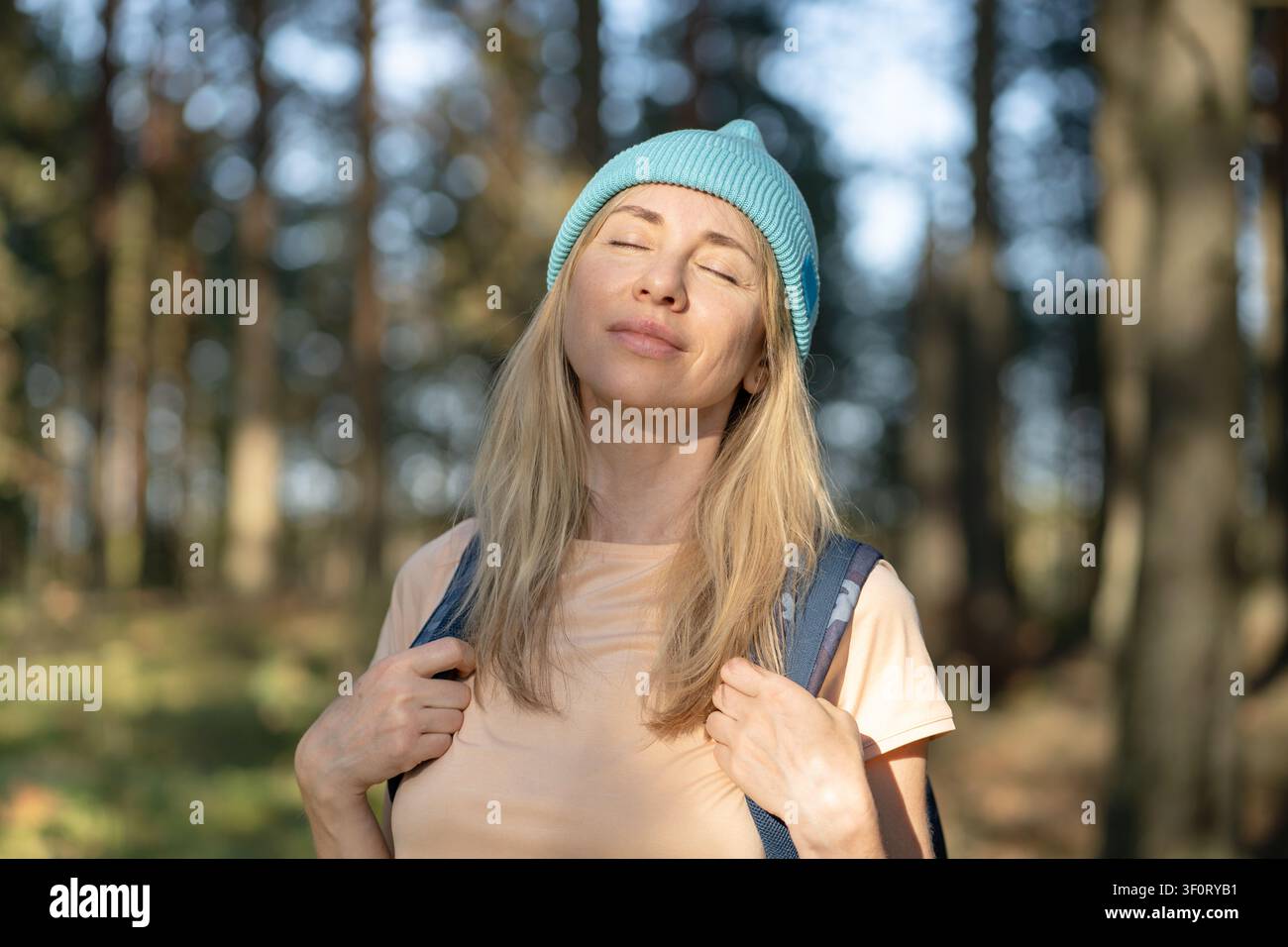 Positiv lächelnde Frau entspannt und betrachtet den Wald während einer Wochenendwanderung im Freien im Sommer. Stockfoto