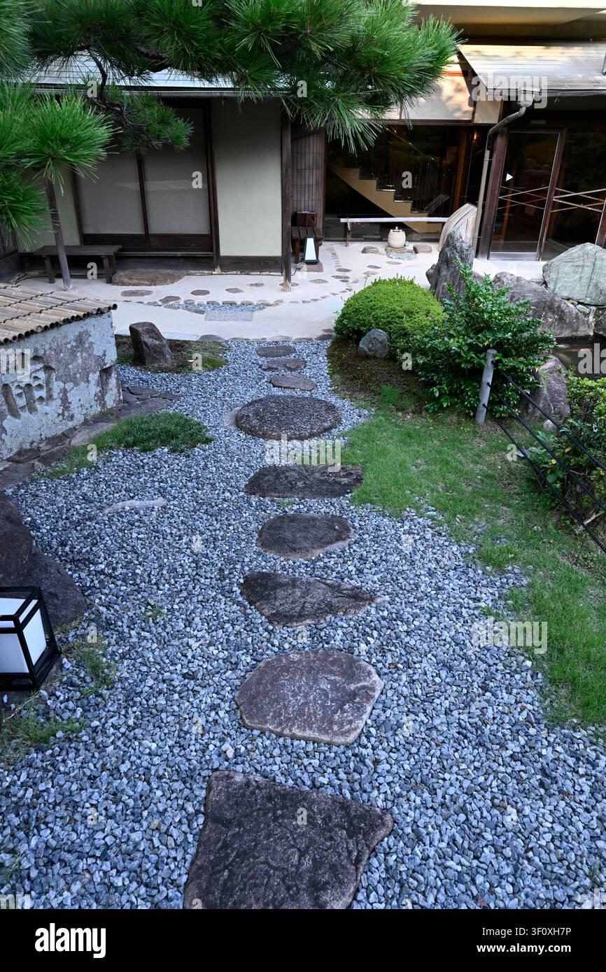 Traditioneller steinerner Treppenweg, der durch den Eingangshof des Hanbe Garden führt, einem renommierten Kaiseki-Restaurant in Hiroshima, Japan. Sorgfältig p Stockfoto