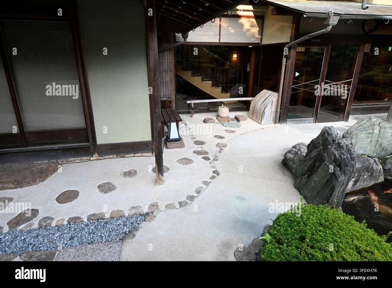 Traditionelle Stein-Trittsteine führen durch einen sorgfältig gestalteten Innenhofgarten im Hanbe Garden, dem historischen Kaiseki-Restaurant in Hiroshima, Ja Stockfoto